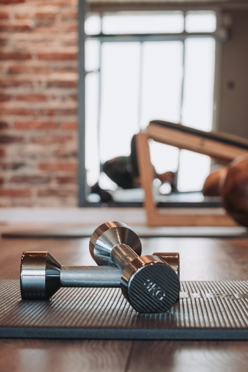 Die Physio Schmiede-Trainingsraum Hanteln Zwei Hanteln liegen auf einer Gymnastikmatte im Trainingsraum einer Physiotherapiepraxis.